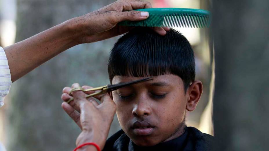 Garoto em barbearia a céu aberto, em Bangladesh