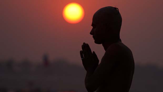 Devoto oferece orações ao Deus Sol onde os rios Ganges, Yamuna e Saraswati se encontram, na Índia