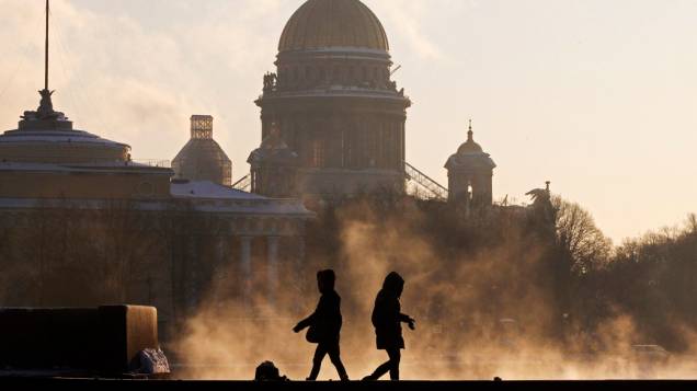 Pessoas caminham à margem do rio Nieva em frente à catedral de São Isaac, em São Petesburgo, Rússia, sob temperatura abaixo do -20°