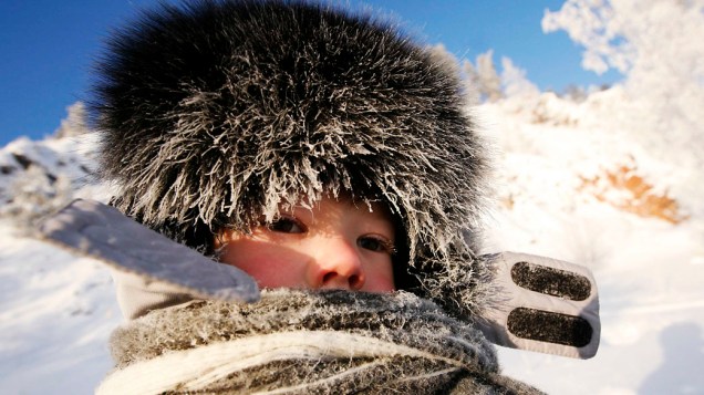 Criança se protege do frio de -30°C às margens do rio Yenisey na cidade siberiana de Krasnoyarsk, Rússia