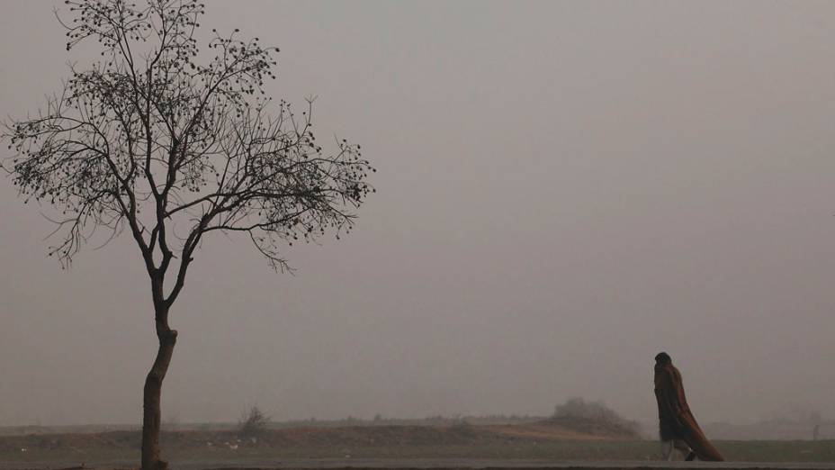 Homem caminha por uma estrada em meio à densa neblina, nos arredores de Islamabad, Paquistão