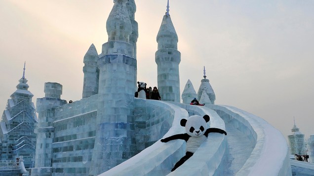 Um trabalhador fantasiado de panda desliza em escultura de gelo durante o festival de neve em Harbin, na China