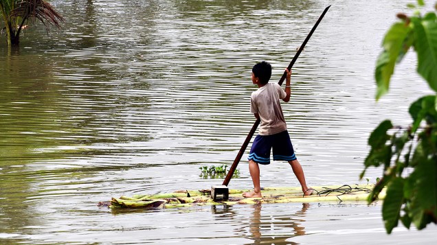 Jangada improvisada feita de bananeira é usada por um menino em uma vila inundada causada ​​por fortes chuvas no sul da ilha de Mindanao, nas Filipinas