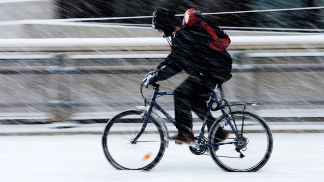 Ciclista pedala em calçada tomada pela neve em Genebra, na Suíça, nesta terça-feira (15)