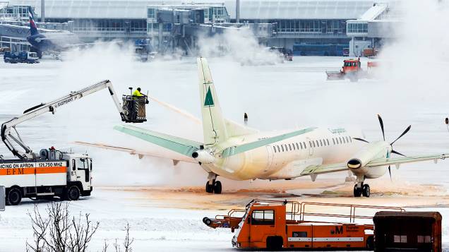 Funcionários descongelam avião na pista do aeroporto de Munique (Alemanha). Diversos voos foram cancelados no aeroporto devido às condições climáticas