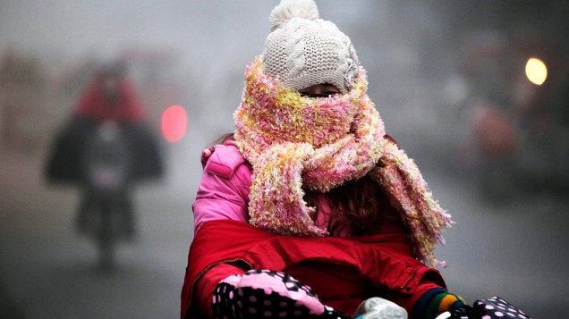 Uma mulher se protege do frio em Haozhou, província de Anhui, na China
