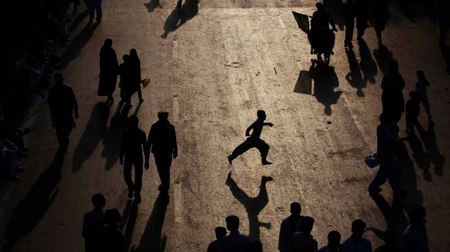 Silhueta de menino correndo durante procissão em comemoração ao aniversário do profeta Maomé em Karachi, Paquistão
