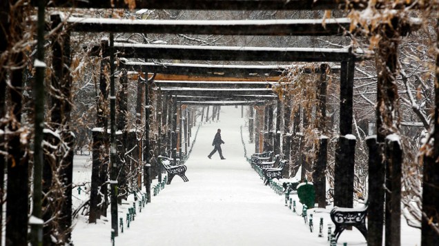 Homem caminha em parque coberto de neve em Bucareste, Romênia
