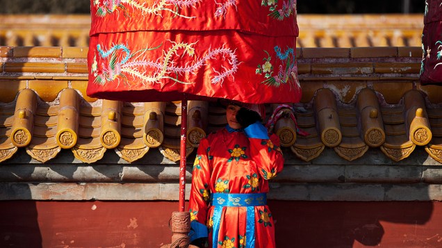Menino se protege do sol próximo a um templo em Pequim (China), nesta sexta-feira (8). O país se prepara para receber o Ano-Novo lunar, em 10 de fevereiro