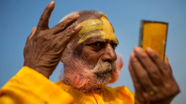 Hindu pinta o rosto durante as festividades do Kumbh Mela, na Índia