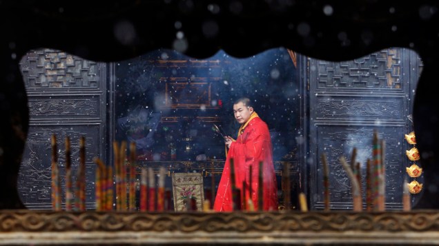 Monge é visto através de um queimador de incenso dentro de um templo em Jiaxing, província de Zhejiang, China