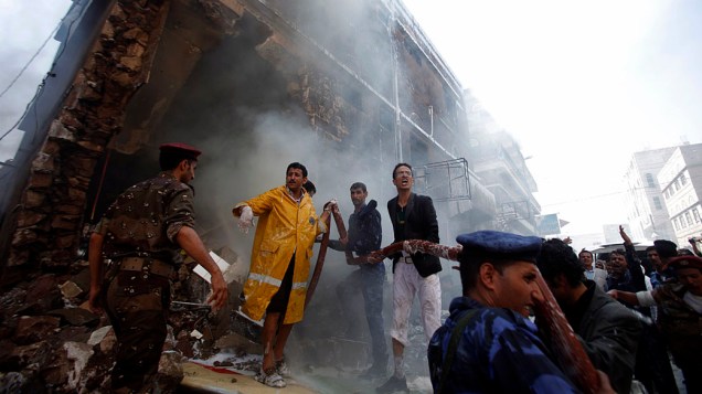Militares e bombeiros trabalham para apagar um incêndio no local de um acidente de avião militar, que deixou ao menos 11 mortos, em Sanaa, Iêmen
