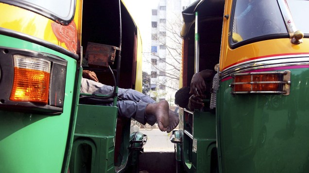 Condutores de Riquixás dormem em seus veículos perto de Nova Délhi, Índia