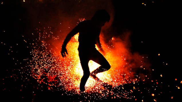 Vietnamita salta em um ritual de fogo durante uma cerimônia em tribo próxima de Hanói