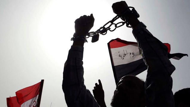 Manifestante egípicio prende suas mãos com correntes para simbolizar a falta de liberdade no país, durante protesto no Cairo