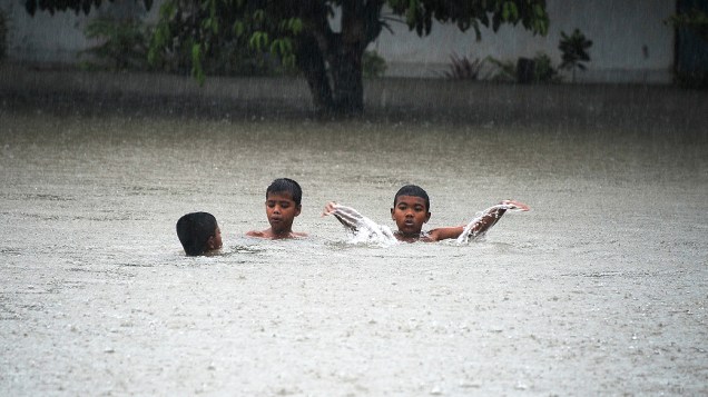 Garotos brincam em rua inundada durante tempestade na província de Narathiwat, no sul da Tailândia, nesta terça-feira (26)