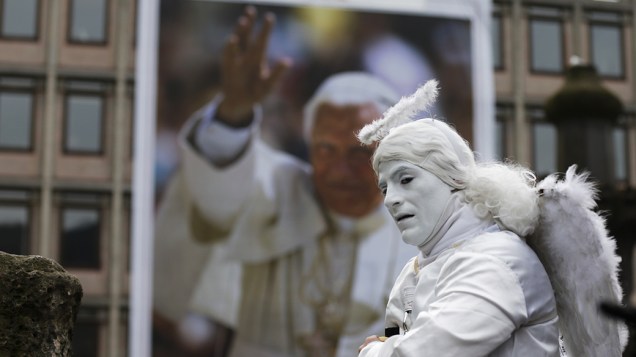Artista de rua posa em frente a uma fotografia do Papa Bento XVI numa loja nas ruas de Roma