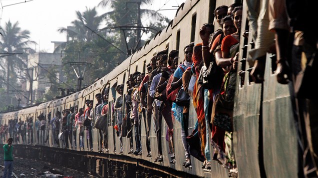 Passageiros se penduram em portas de trem superlotado em Calcutá, na Índia. O sistema de trem indiano é um dos maiores do mundo