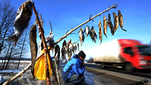 Vendedor de peixes aguarda à beira de uma rodovia em Lapichi, vila bielorrussa a 95 km de Minsk
