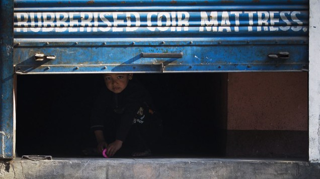 Criança olha através da porta de uma loja durante greve geral em Katmandu, Nepal