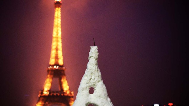 Uma Torre Eiffel feita na neve é fotografada em frente à Torre Eiffel em Paris. Tempestades de neve inesperadas para a época atingiram a Europa, incluindo Espanha e França
