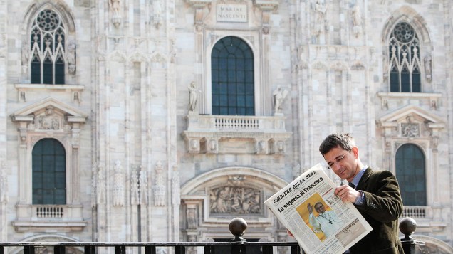 Homem lê um jornal italiano que mostra o Papa recém-eleito, Francisco I,  na praça Duomo, centro de Milão