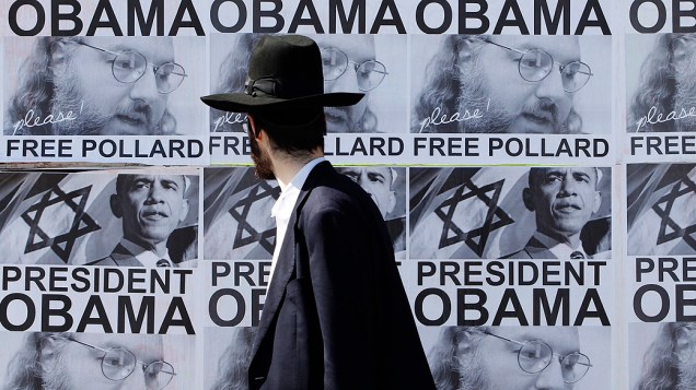Judeu ultra ortodoxo passa diante de cartazes pedindo para o presidente Barack Obama a libertar Jonathan Pollard de uma prisão norte-americana