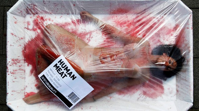 Ativista do grupo Igualdade Animal, que luta pelos direitos dos animais, se apresenta em uma bandeja gigante de carne no Dia Mundial sem Carne na praça da catedral de Barcelona, Espanha