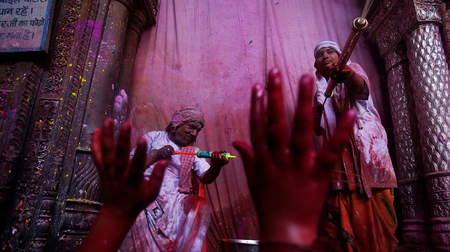Sacerdotes hindus jogam spray de água colorida sobre devotos durante as celebrações Holi, Festival das cores, no templo de Bihari Bankey, em Uttar Pradesh, Índia