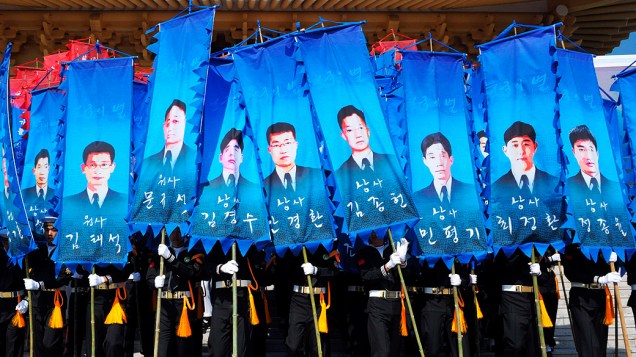 Guardas de Honra sul-coreanos seguram bandeiras com imagens dos marinheiros que morreram no naufrágio de um navio em Seul, durante evento que marca o terceiro aniversário do acidente, no cemitério nacional em Daejeon