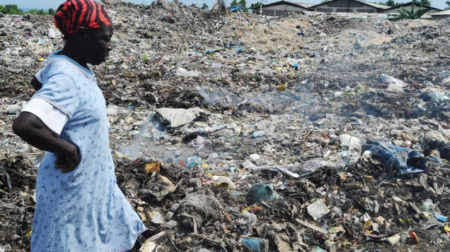 Mulher procura objeto para reciclar em um lixão no Haiti
