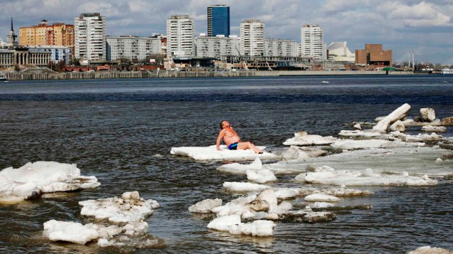 Homem toma sol sobre uma placa de gelo no rio Yenisei, na Rússia