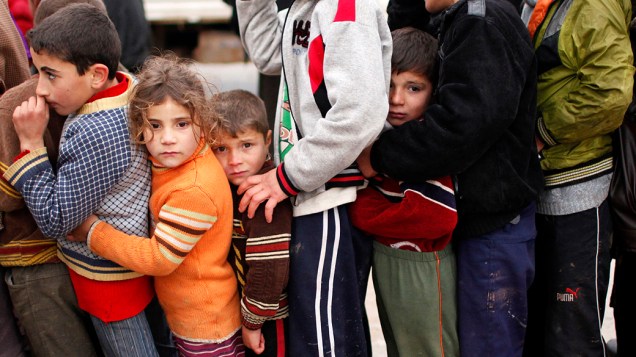 Crianças esperam para receber alimentos e ajuda em campo de refugiados na cidade de Bab al-Salam, na Síria