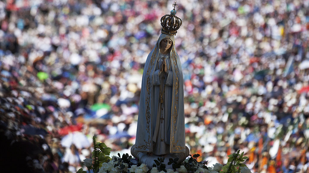 Peregrinos participam de procissão no santuário de Nossa Senhora do Rosário de Fátima, em Portugal nesta segunda-feira (13)