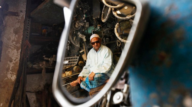 Vendedor de peças de carro usadas, sentado em sua loja em Nova Délhi, na Índia