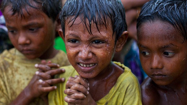 Crianças de famílias da etnia Rohingya tomam chuva em acampamento improvisado para pessoas que foram deslocadas de suas casas com a aproximação do ciclone Mahasen, nesta terça-feira (14), em Sittwe, no Mianmar