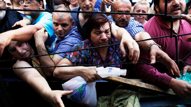 Pessoas se amontoam para levar frutas e legumes distribuídos gratuitamente pelos vendedores do mercado de rua, em protesto simbólico contra os planos do governo para mudar o status de suas licenças, em Atenas, na Grécia