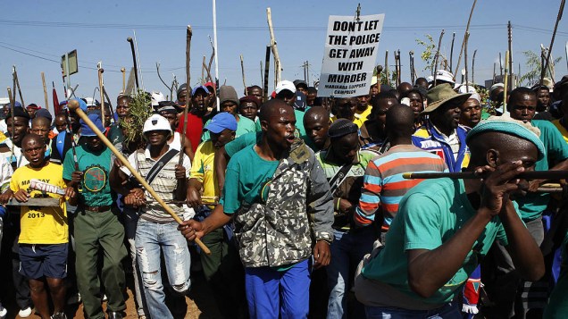 Membros de uma comunidade mineira marcham durante uma greve na mina de platina de Marikana Lonmin em Rustenburg, África do Sul
