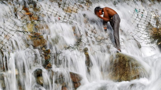Menino toma banho em um córrego de Dara, nos arredores de Srinagar, região da Caxemira