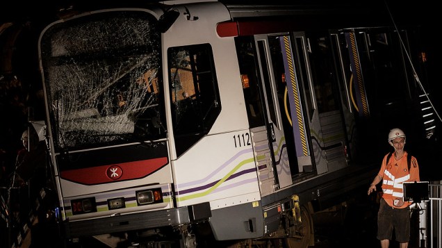 Trabalhador passa por um trem que descarrilou em Hong Kong. Sessenta e duas pessoas ficaram feridas quando vários carros descarrilaram na estrada de ferro luz de Hong Kong