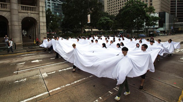 Pessoas dentro de um pano branco participam da obra de arte Divisor, da artista brasileira Lygia Pape, em Hong Kong