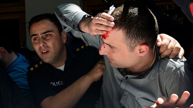 Policial ajuda homem ferido durante confrontos em um Dia Internacional Contra a Homofobia e Transfobia, na Geórgia 