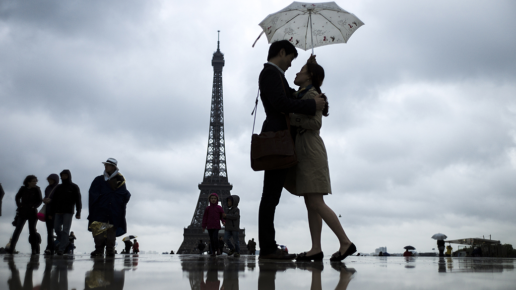 Movimentação na Praça do Trocadéro, em frente à Torre Eiffel, em Paris durante um dia chuvoso
