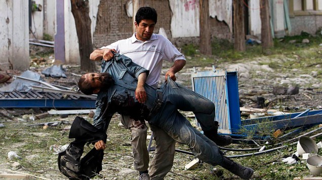 Um policial ferido é carregado para longe do local de uma explosão em Cabul. Várias grandes explosões atingiram uma área movimentada no centro da capital, testemunhas descrevem tiroteio na área, no Afeganistão