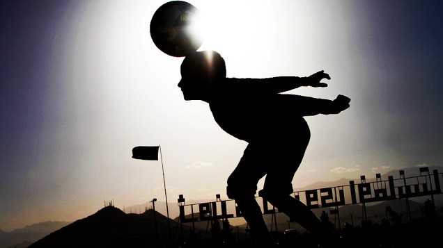 Um menino afegão brinca com a bola na colina de Naderkhanem, em Cabul, no Afeganistão