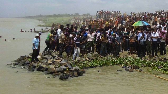 Moradores ficam nas margens do rio Ganges após o naufrágio de uma balsa no distrito de Malda. A balsa estava superlotada com dezenas de pessoas e animais virou matando pelo menos dois e deixando 25 desaparecidos