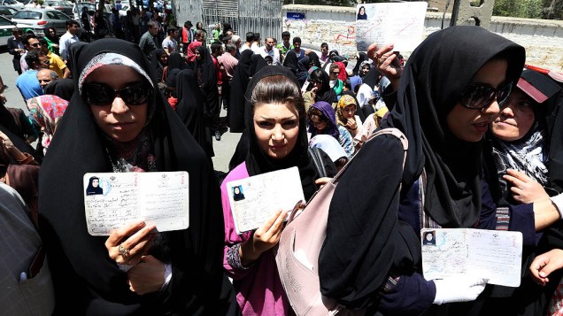 Mulheres iranianas mostram seus documentos em uma fila para votar no primeiro turno da eleição presidencial no Teerã, quatro anos após a polêmica reeleição de Mahmoud Ahmadinejad