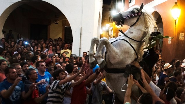 Um cavalo empina em uma multidão durante um desfile de cavalos do tradicional Festival San Juan, em Ciutadella de Menorca, na Espanha