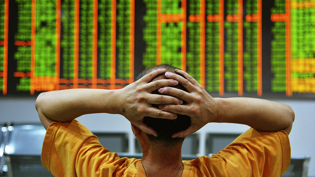 Investidor se senta na frente de um painel eletrônico que mostra informações sobre ações em uma corretora em Hangzhou, província de Zhejiang, na China