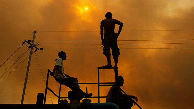 Trabalhadores observam queima de árvores plantadas para o óleo de palma,  no distrito de Bangko Pusako, em Rokan Hilir, Indonésia